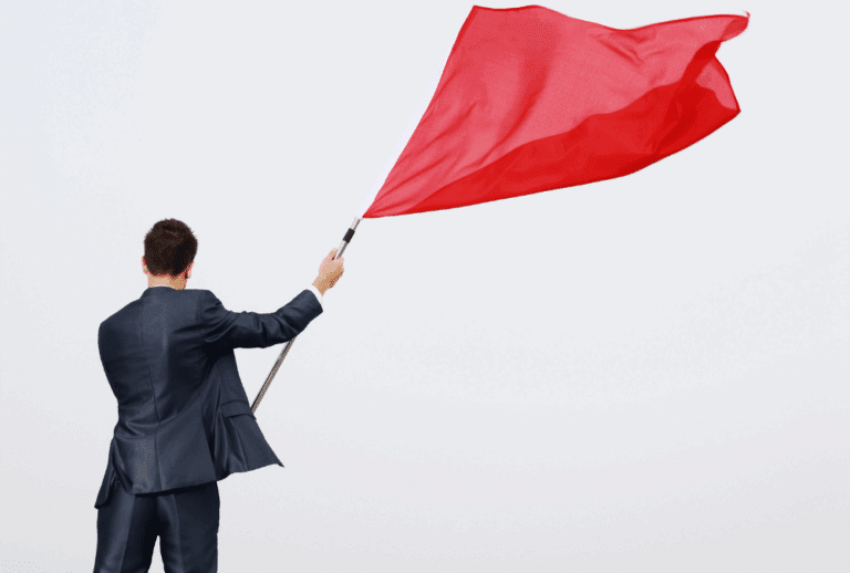 Image is of a businessman waving a red flag, concept of red flag to look for in job candidates