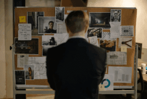 Image is of an investigator in front of a board, concept of how investigators find missing persons