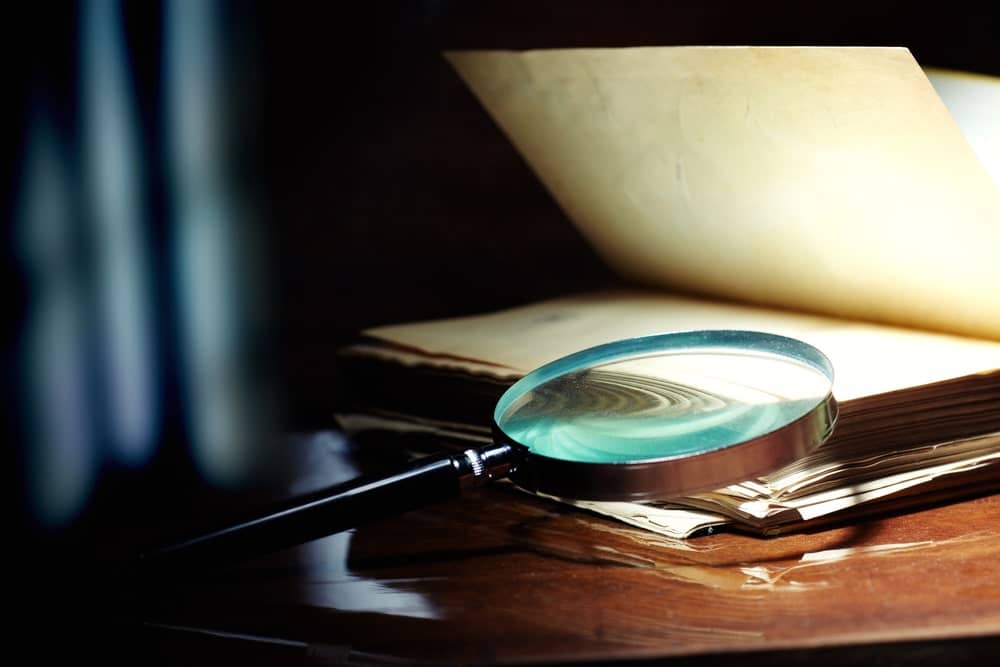 Magnifying glass on old documents symbolizing investigation into property ownership records