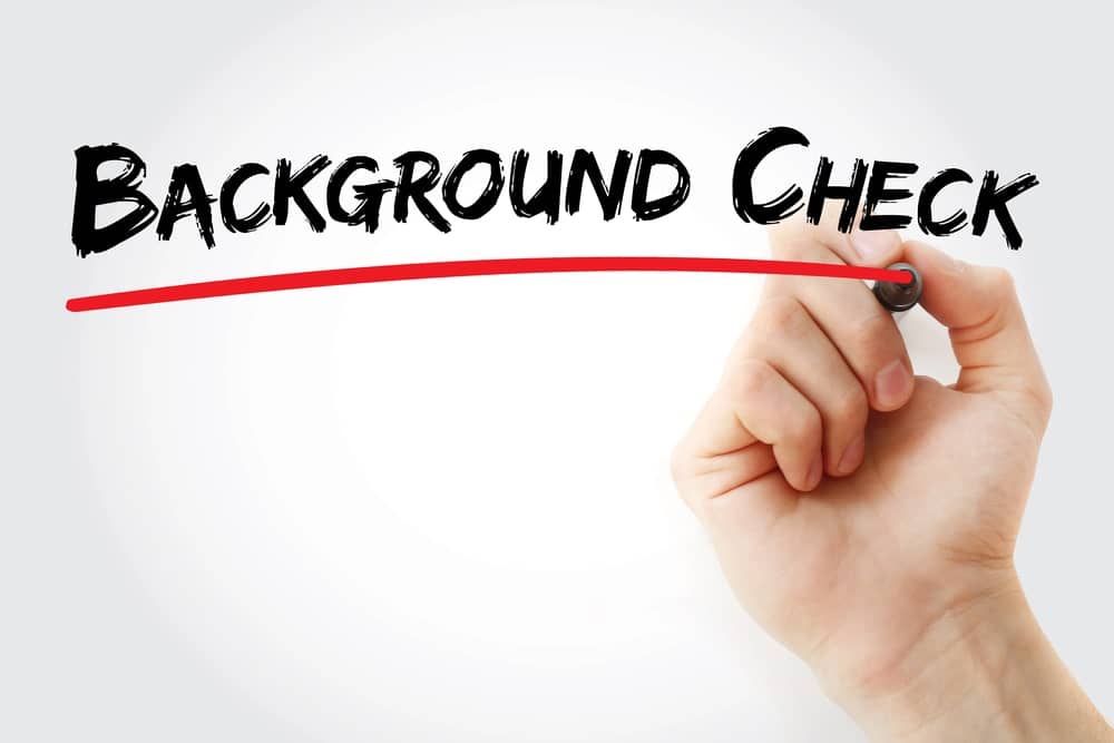 Hand writing background check with red underline showing washington background checks concept