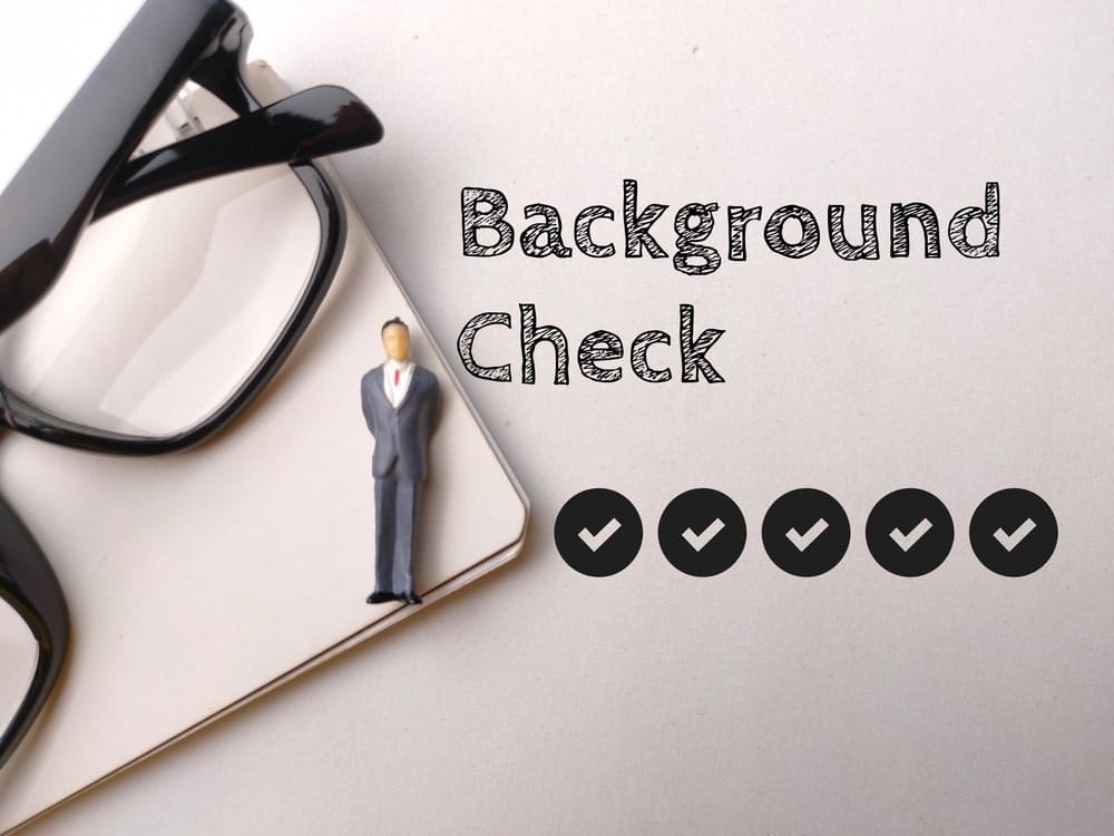 Miniature businessman beside eyeglasses representing professional washington background checks for employment screening