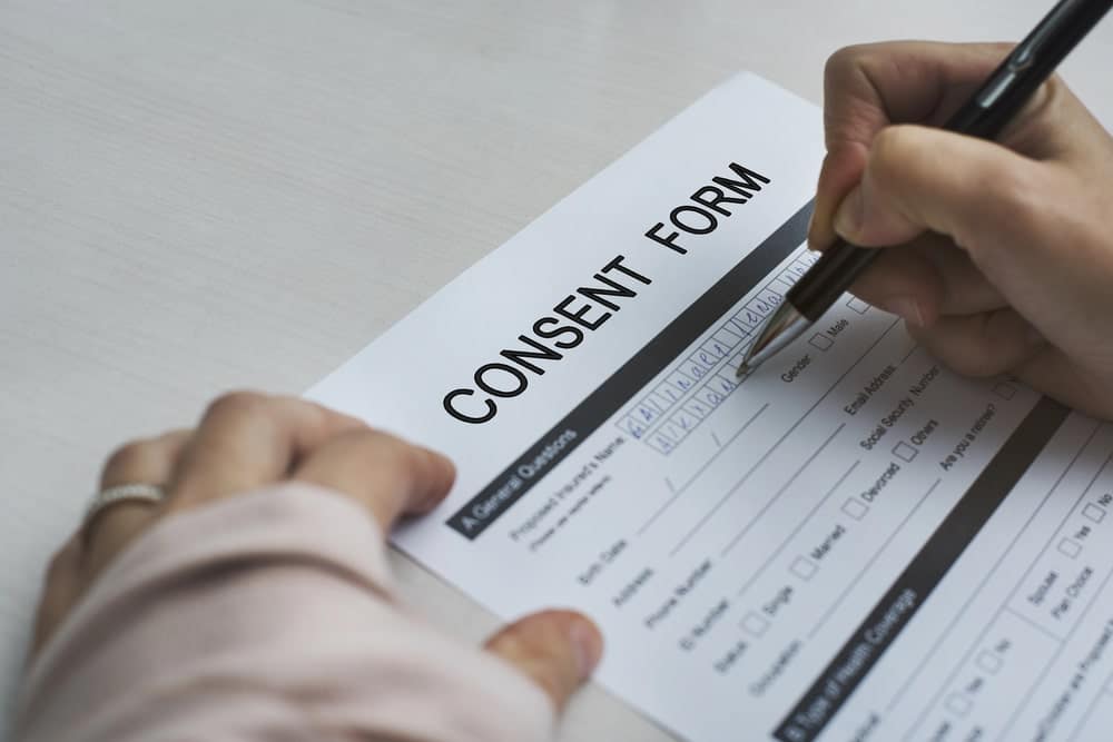 Image shows a person filling out a consent form, representing the written disclosures Seattle property managers must provide before conducting a tenant background check.