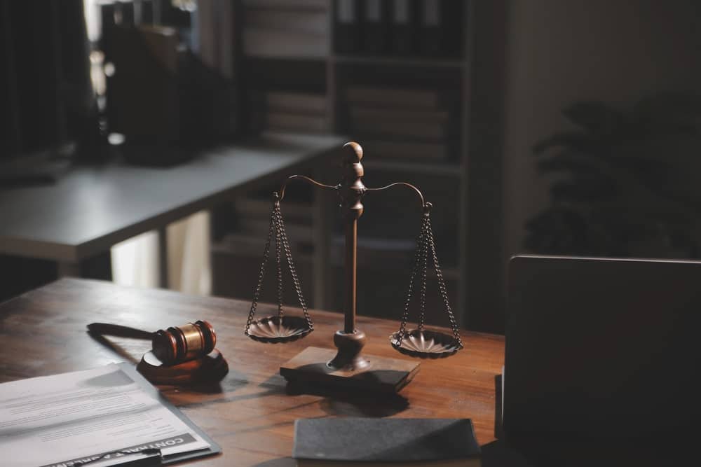 Image shows scales of justice and a gavel on a desk, symbolizing legal standards Seattle landlords must follow during a tenant background check.