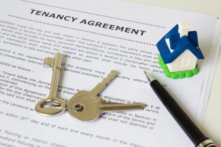 Image shows a tenancy agreement with house keys and a small model home, illustrating how documents affect rental decisions during a tenant background check.