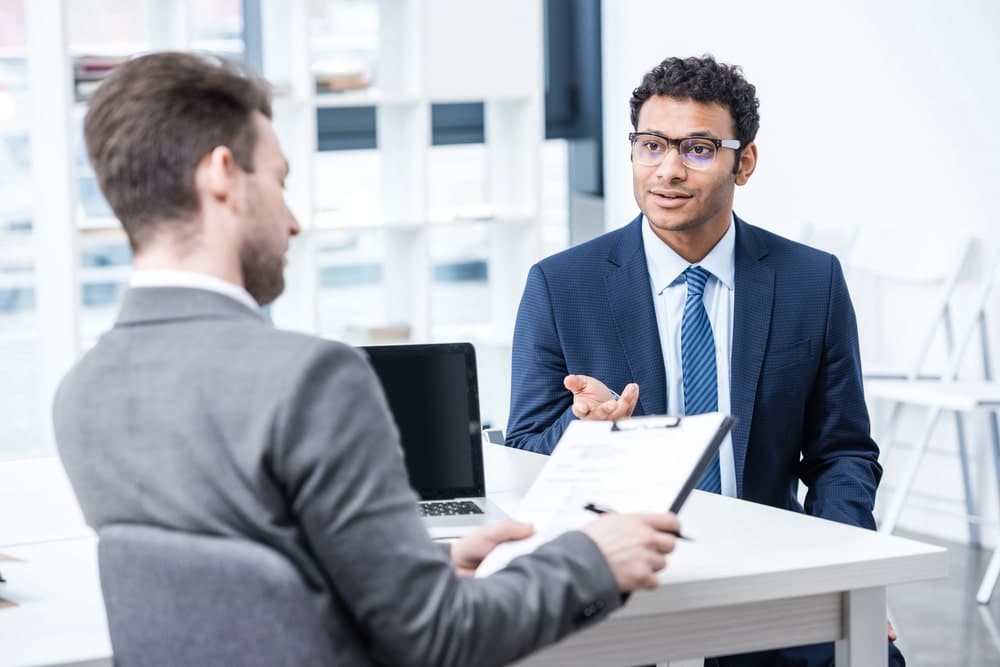 Image shows an employer interviewing a candidate in an office setting, illustrating how Washington companies review applicants and conduct background checks during the hiring process.