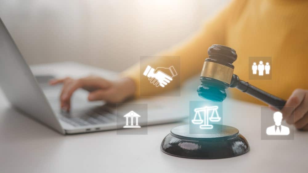 Image shows a person using a laptop with a judge’s gavel on the desk and digital legal icons glowing above it, representing how employers use background checks while following Washington hiring laws.