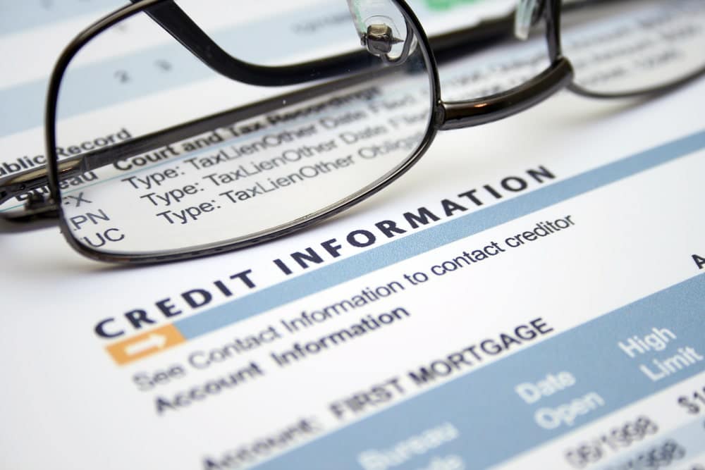 Image is of a close up credit information document with glasses placed on top, concept of employers analyzing credit reports during background checks.