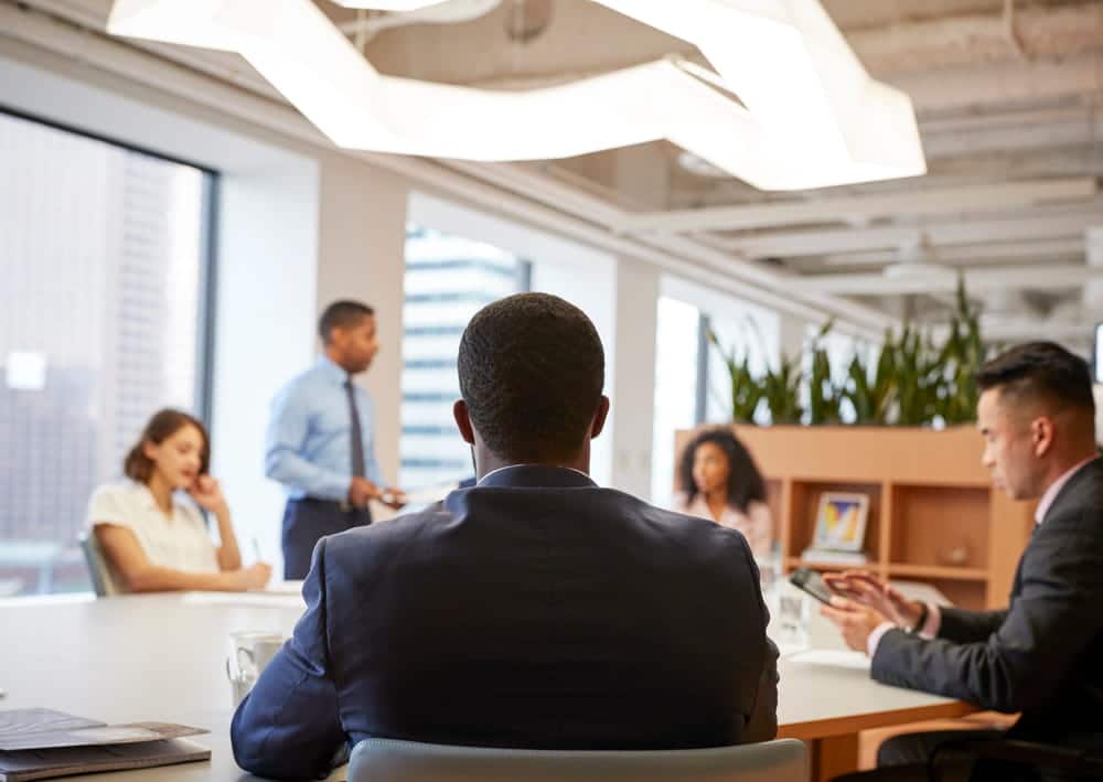Image is of a candidate seated before a hiring panel in an office meeting room, illustrating job interviews and employment in WA