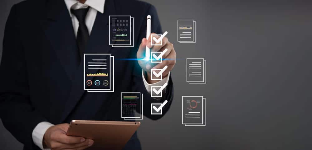 Image is of a business professional reviewing digital documents and compliance reports on a tablet, concept of data verification and WA checks