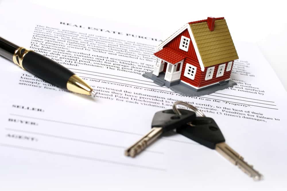 Image is of a miniature house, keys, and signed property documents, concept of financial disclosures reviewed in an asset search report.