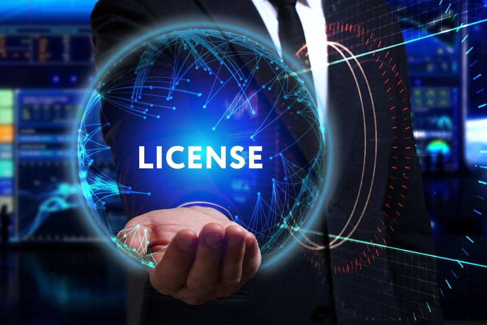 Image is of a businessman holding a glowing digital globe with the word license, representing a background check for professional credentials.